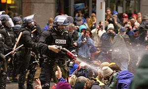 Agentes de policía usando gas pimienta contra manifestantes contrarios a la WTO/OMC